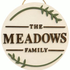 Round custom family name sign with raised lettering and sage green leaf accents