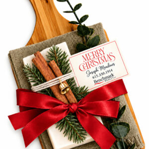 Walnut cutting board with green fringed kitchen towel, evergreen bar soap, and red satin bow
